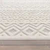 A close-up view of a textured rug with a geometric pattern, placed on a wooden deck. Voir les images du produit