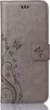 A gray flip case for a phone with a floral and butterfly embossed design. Produktbild-Vorschau