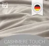 A close-up of soft, textured fabric, likely bedding, with overlaid text and a German brand logo. Voir les images du produit