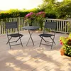 A balcony or patio setting with a small table and two chairs, surrounded by plants and a railing. Voir les images du produit