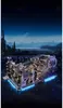 A futuristic city skyline at dusk with a complex mechanical model in the foreground, illuminated by blue lights. Podgląd zdjęcia produktu