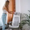 A woman is adjusting a massage mat placed on a chair in a room. Produktbild-Vorschau