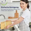 A woman is washing a bamboo cutting board in a kitchen sink. Produktbild-Vorschau