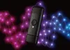 A black Twinkly Music Dongle is shown in the center, with abstract wavy lines of pink and blue lights on a black background. Náhled obrázku produktu