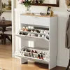 A white shoe cabinet with two flip-down doors, displaying shoes inside, placed in a hallway or entryway. Produktbild-Vorschau