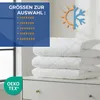 A stack of white, quilted blankets on a white dresser, with a blue overlay box listing sizes and a sun/snowflake icon. Produktbild-Vorschau