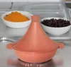 A terracotta tajine pot is centered in the foreground, with bowls of orange puree and dark purple ingredients in the background. Voir les images du produit