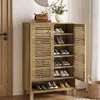 A wooden shoe cabinet with its door open, displaying shoes on shelves. A woven basket and a vase with flowers are on top of the cabinet. Produktbild-Vorschau