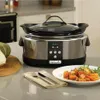 A Crockpot slow cooker is shown on a kitchen counter, with a plate of food and cutlery in the foreground. Produktbild-Vorschau
