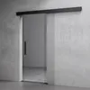 A modern glass sliding door with a black handle against a concrete wall.