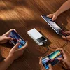 A power bank is charging multiple devices on a wooden table. Produktbild-Vorschau