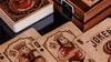 A close-up view of several playing cards and a deck of cards on a dark, reflective surface. Náhľad obrázku produktu