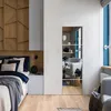Modernes Schlafzimmerinterieur mit einem Bett, Holzvertäfelung an der Wand, einem weißen Nachttisch und einer verspiegelten Tür Anteprima dell’immagine prodotto