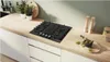 A modern kitchen countertop with a black gas hob, plants, and kitchen utensils. Anteprima dell’immagine prodotto
