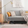 A treadmill is placed under a sofa in a living room, with a floor lamp and decorative pillows. Náhled obrázku produktu