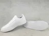 A pair of white Adidas sneakers on a gray concrete background. Voir les images du produit