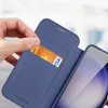 A hand is inserting a credit card into a blue phone case with a card slot. Voir les images du produit