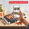A hand holding a smartphone displaying recipes, with a Tefal grill and food in the foreground. Produktbild-Vorschau