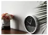 A clock and a bouquet of roses are displayed on a wooden surface against a white wall. Podgląd zdjęcia produktu