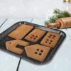 Gingerbread house pieces on a baking tray with a rolling pin and pine branches in the background. Voir les images du produit