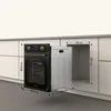 An oven is shown partially installed in a kitchen cabinet, with dimensions indicated. Podgląd zdjęcia produktu