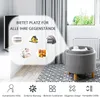 A marketing image showing a round storage ottoman with a tray on top, placed on a patterned rug in a room setting. Produktbild-Vorschau