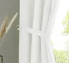 A close-up of a white curtain with a tie-back, next to some dried grass in a vase. Produktbild-Vorschau