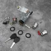 A collection of car ignition lock components and keys laid out on a textured gray surface. Podgląd zdjęcia produktu