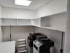 An empty office storage area with shelves and printers. Produktbild-Vorschau