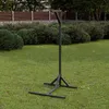 A black metal hammock stand is set up on a green lawn in front of bushes and a fence. Podgląd zdjęcia produktu
