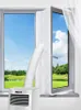 A portable air conditioner unit with an exhaust hose connected to a window seal kit, set up in a room with a view of a natural landscape. Podgląd zdjęcia produktu