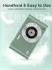 A green digital camera is shown against a light blue and white background with feather graphics. Produktbild-Vorschau