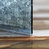 A close-up view of a shower door seal with water droplets on it, resting on a tiled floor. Produktbild-Vorschau