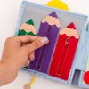 A hand is shown interacting with a felt quiet book for babies, specifically zipping up a purple pencil-shaped pocket. Produktbild-Vorschau