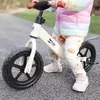 A child is riding a balance bike outdoors on a gravel path. Náhled obrázku produktu