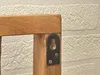 A close-up view of a wooden coat rack with a metal mounting bracket attached to it, set against a textured white brick wall. Produktbild-Vorschau