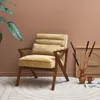 A stylish armchair in a room with a terracotta-colored wall and a patterned rug. Produktbild-Vorschau