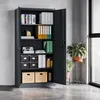 An open, dark gray metal filing cabinet filled with office supplies, standing in a modern office or studio setting. Produktbild-Vorschau