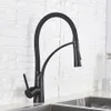 A black kitchen faucet with a flexible hose is shown in use, with water running into a sink. Produktbild-Vorschau