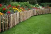 A rustic wooden fence borders a vibrant flower garden and a lush green lawn. Produktbild-Vorschau