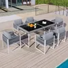 An outdoor patio set with a table and chairs, set on a wooden deck next to a pool. Produktbild-Vorschau