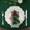 A festive Christmas table setting with plates, cutlery, a napkin, holly, and a candy cane cookie. Produktbild-Vorschau