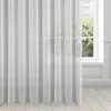 A white sheer curtain hangs in front of a window with greenery visible outside. Produktbild-Vorschau