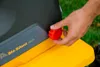 A hand is shown turning a red knob on a yellow and gray garden shredder. Produktbild-Vorschau