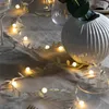 A string of LED lights with leaf-shaped decorations is draped across a table setting with glasses and a vase. Produktbild-Vorschau