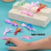 Auswahl an bunten dehnbaren Dinosaurierspielzeugen, ein pinker Dinosaurier zwischen den Fingern gestreckt Produktbild-Vorschau