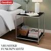 A bedside table next to a bed, with a lamp, book, and cup on top. Anteprima dell’immagine prodotto