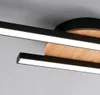 A close-up view of a modern LED ceiling light fixture with black metal accents and a wooden element. Produktbild-Vorschau