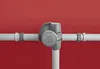 A close-up view of a gray valve mechanism attached to a white pipe, set against a plain red background. Produktbild-Vorschau