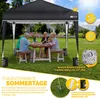 A family is enjoying a meal under a black pop-up gazebo in a grassy backyard. Produktbild-Vorschau